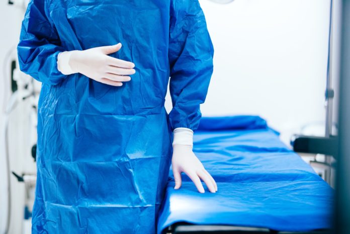 Details of surgeon scrubs, rubber gloves and operating table. Portrait of surgeon Details of surgeon scrubs, rubber gloves and operating table. Portrait of surgeon