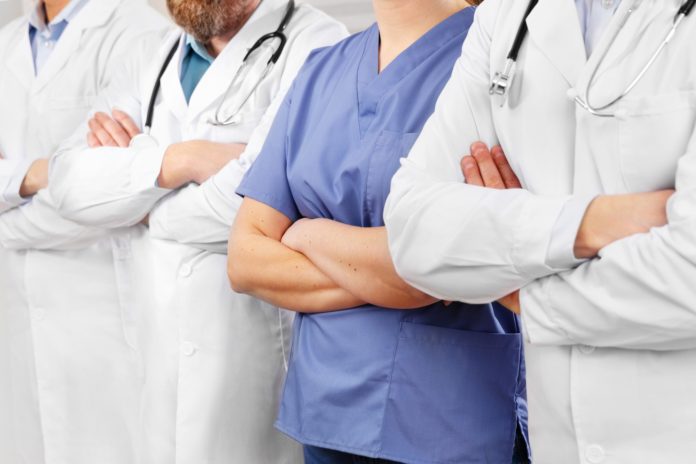 Doctors and nurses in healthcare team with arms crossed in a row in hospital Doctors and nurses in healthcare team with arms crossed in a row in hospital