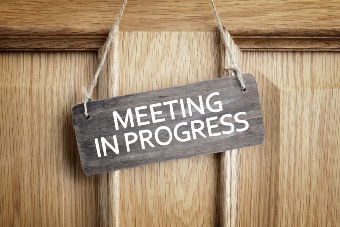 Meeting in progress sign on office door Meeting in progress sign on office door