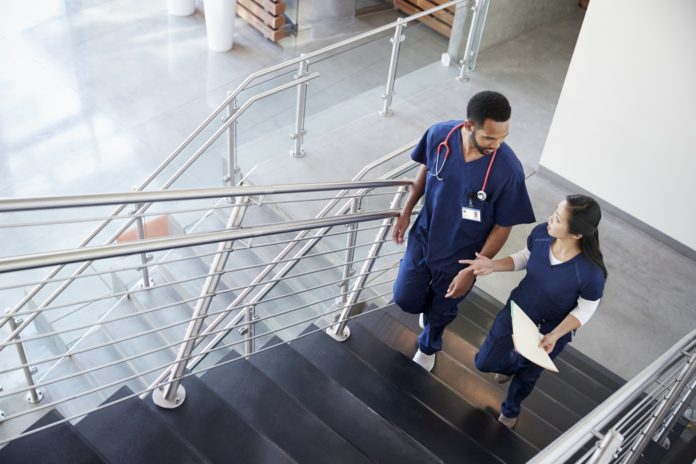 Two healthcare colleagues talking on the stairs at hospital Two healthcare colleagues talking on the stairs at hospital