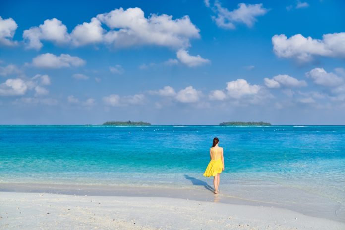 Woman in dress walking on tropical beach Woman in dress walking on tropical beach